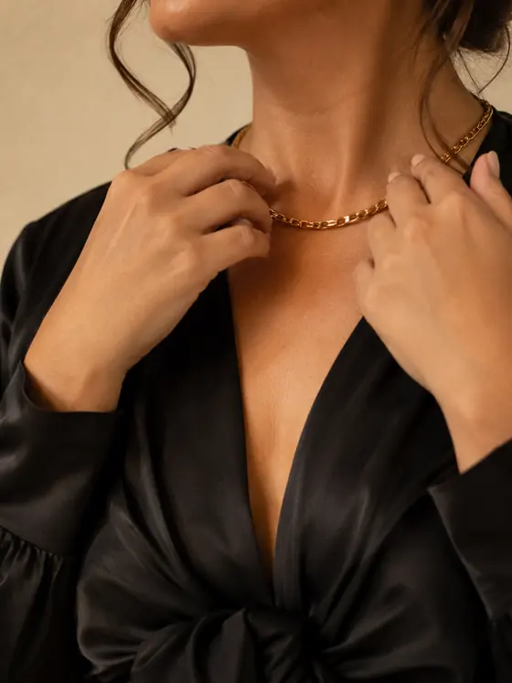 Détail d'un chemisier noir satiné et d'un collier doré